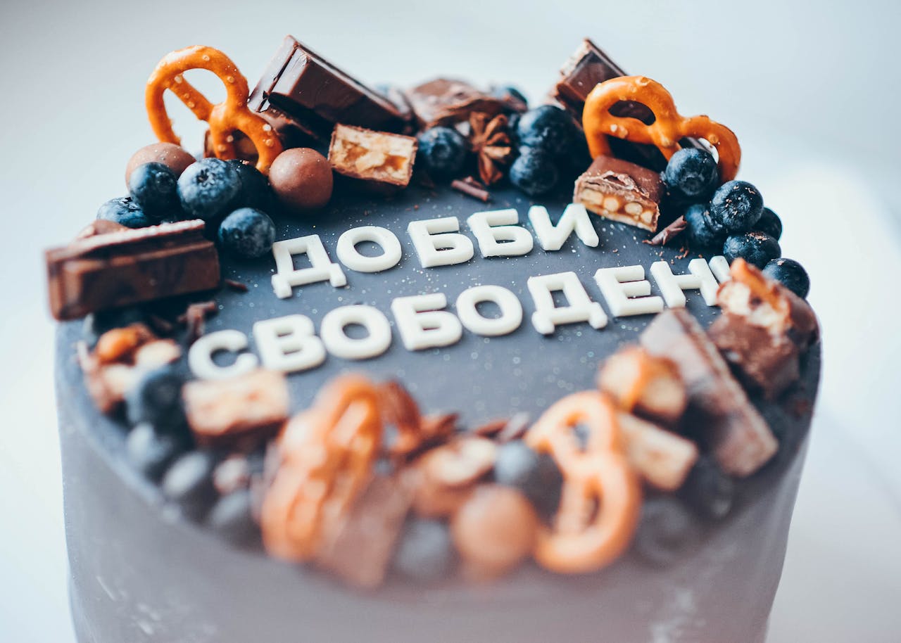 Delicious chocolate cake topped with pretzels, blueberries, and candy bars for a stunning dessert presentation.